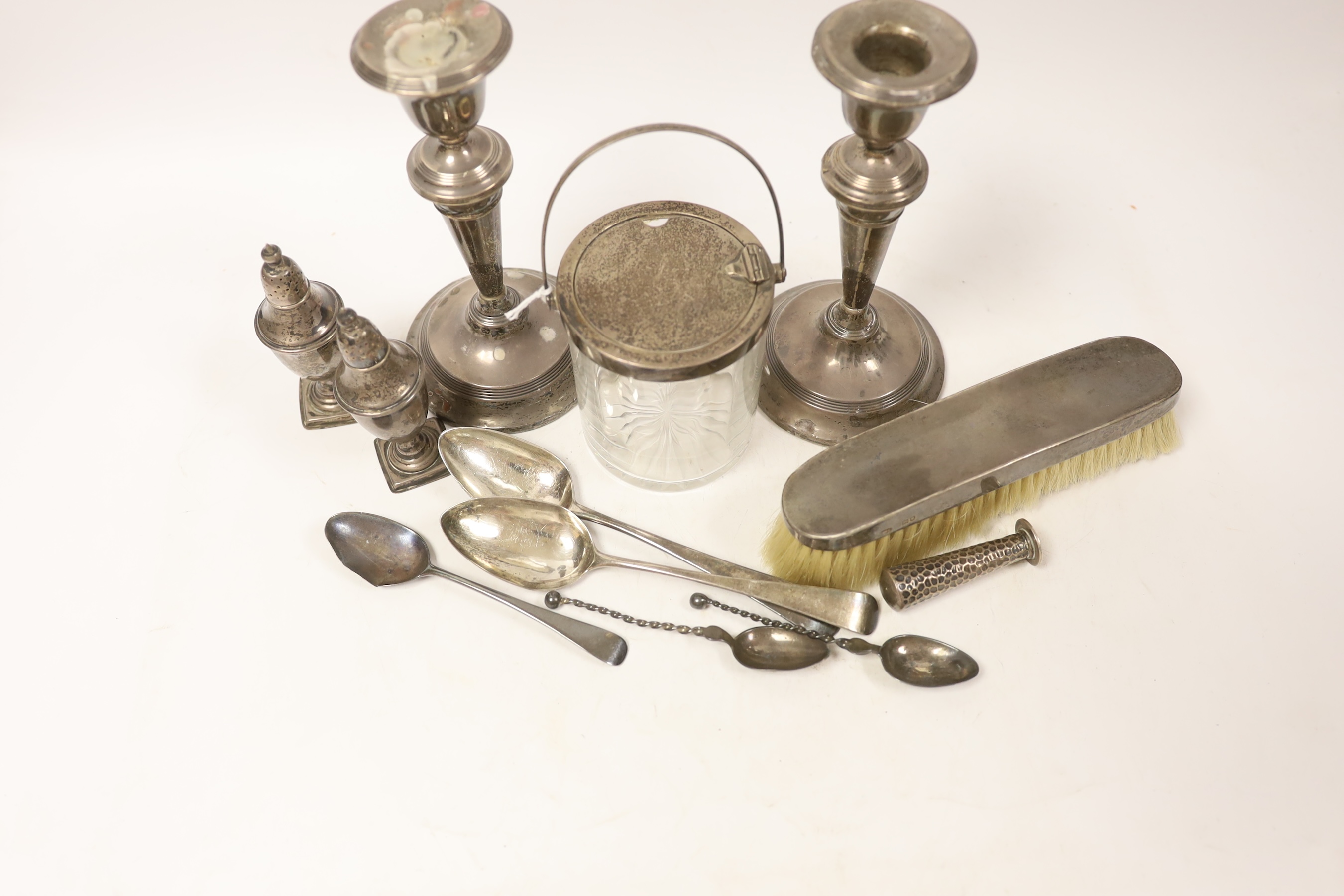 Sundry silver, consisting of three pieces of George III flatware, two 800 standard coffee spoons, a pair of candlesticks(a.f.), a lidded glass preserve pot, clothes brush, two pepperettes and a desk seal.